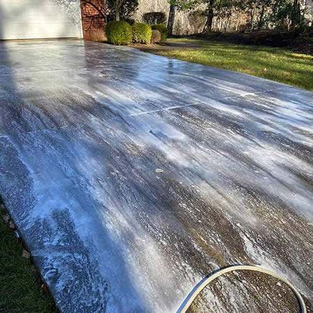 Technician pressure washing a concrete driveway in asheville nc neighborhood